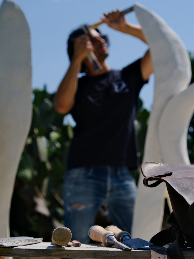 Person working on a sculpture with tools outdoors