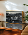 Framed ocean artwork of a sparkly sea on a table with a lamp and plant in the background