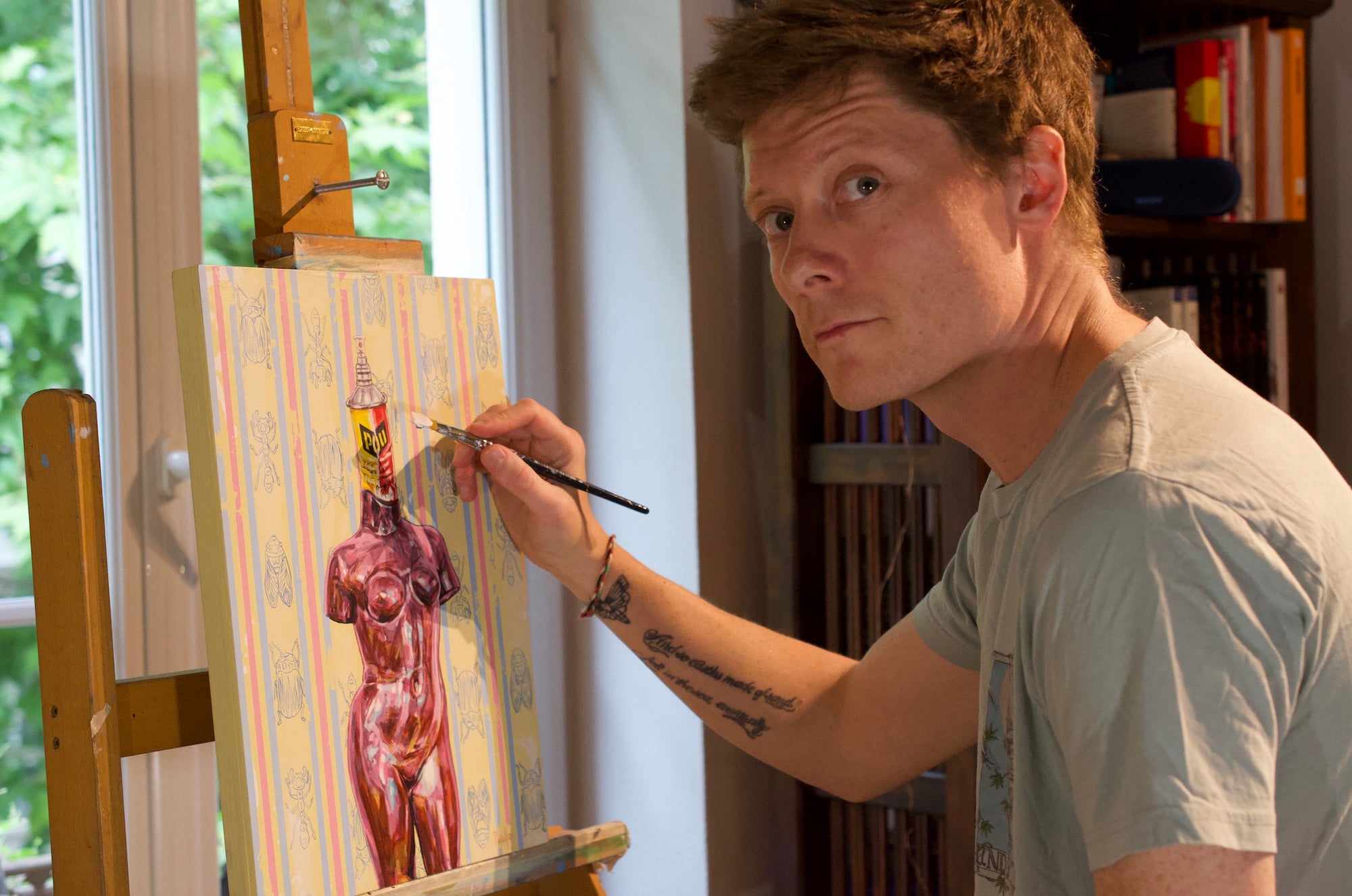 Artist Paul Ward painting a nude figure on an easel indoors