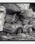 Framed art of a toy car with police design on a pile of newspapers and bags