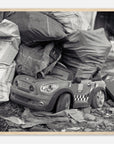 Art print of a toy car among trash bags with a wooden frame