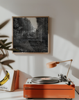 Orange record player on a white surface with a framed black and white artwork on the wall.