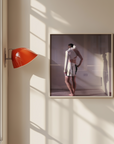 Framed photograph of a person standing in a bathroom on a wall with a red lamp.