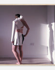 Photo art print of a person wearing a white outfit with black accents in a minimal room.