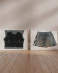 Two framed artworks of a black vest and denim skirt on a wooden floor with a beige wall.