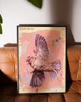 Framed artwork of a bird on a pink background, leaning against a brown leather couch.