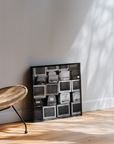 Framed black and white photo print of vintage computer monitors on a wall next to a wicker chair.