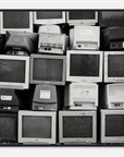 Art print photograph in a black frame depicting a stack of vintage computer monitors in black and white
