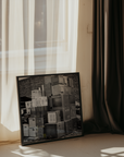Framed black and white photograph of stacked computers leaning against a wall, with curtains in the background.