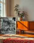 Room interior with a wooden sideboard, plant, and framed artwork on a wall.