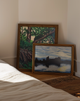 Two framed artworks on a wall next to a bed
