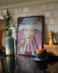 Kitchen counter with a framed portrait, vase, and bowl of fruit against a tiled wall.