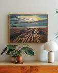 Framed art print of worms head in wales hanging on a wall above a side table with lamp and plants.