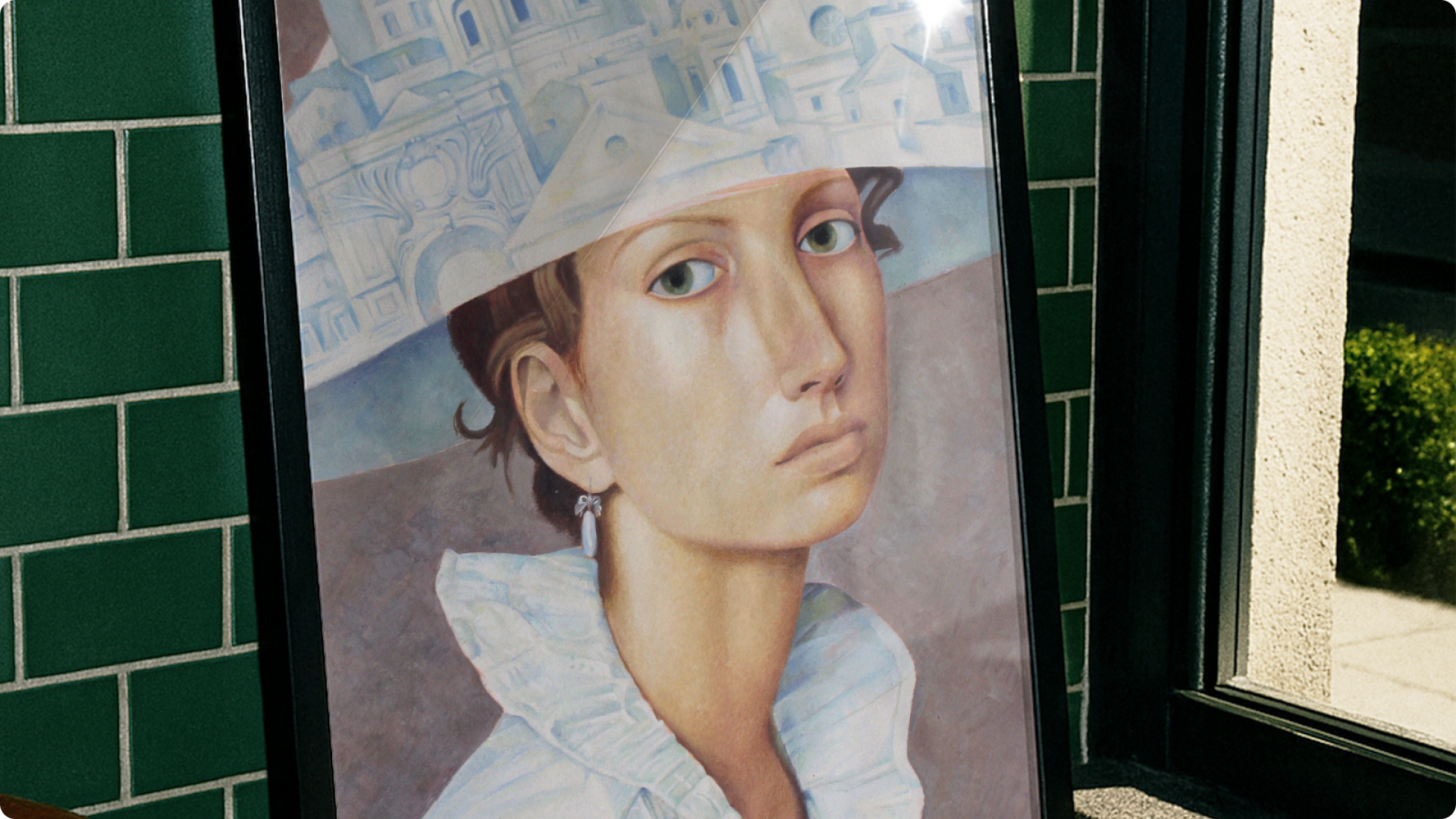 Framed portrait of a woman with a white hat against a green tiled wall.