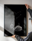 Person hanging a framed black and white artwork on a wall