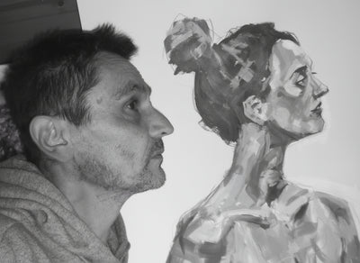 Man looking at a colorful painting of a woman's profile.