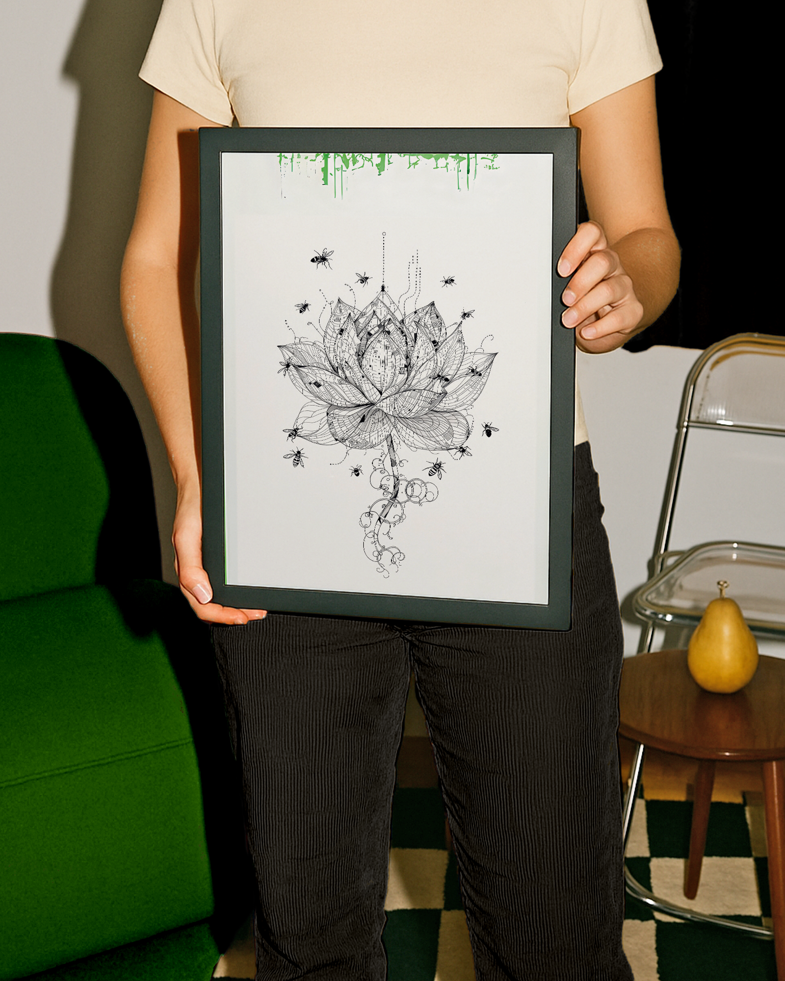 Person holding a framed black and white lotus flower art print in a room with green sofa and wooden table.