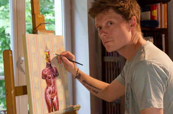 Artist Paul Ward painting a nude figure on an easel indoors