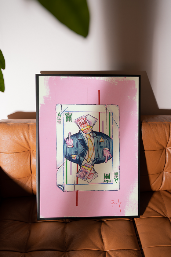 Framed artwork of a person in a card design on a pink background, placed on a brown leather sofa.