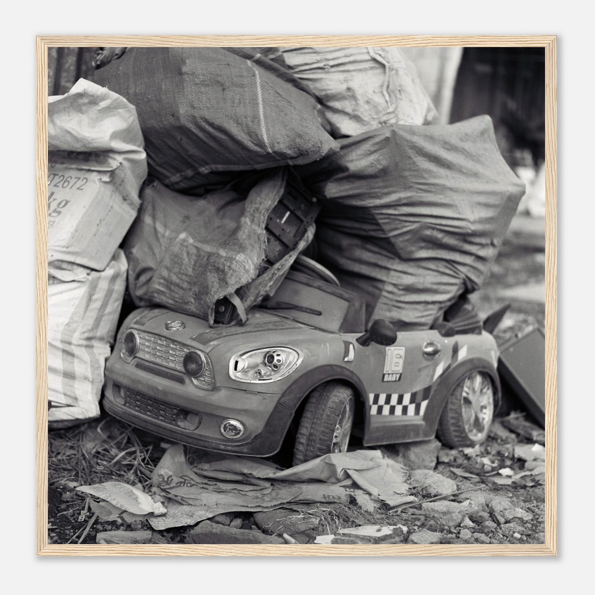 Art print of a toy car among trash bags with a wooden frame