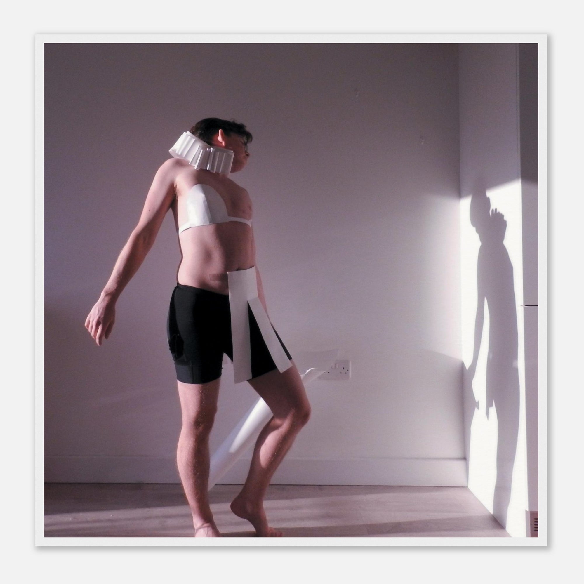 Dance art print of a person wearing a white and black outfit with a neck brace in a room with a light source casting a shadow.