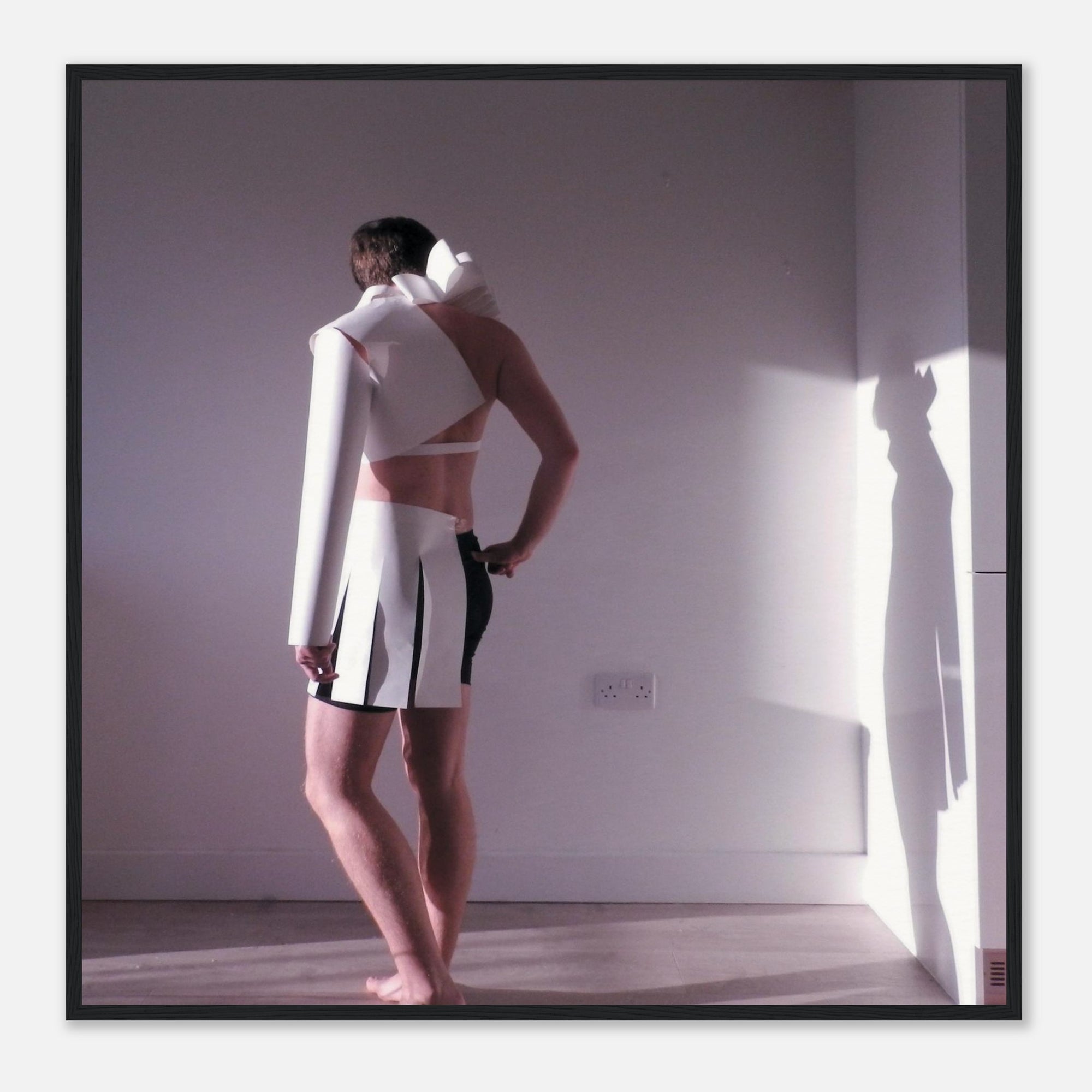 Photo art print of a person wearing a white outfit with black accents in a minimal room.