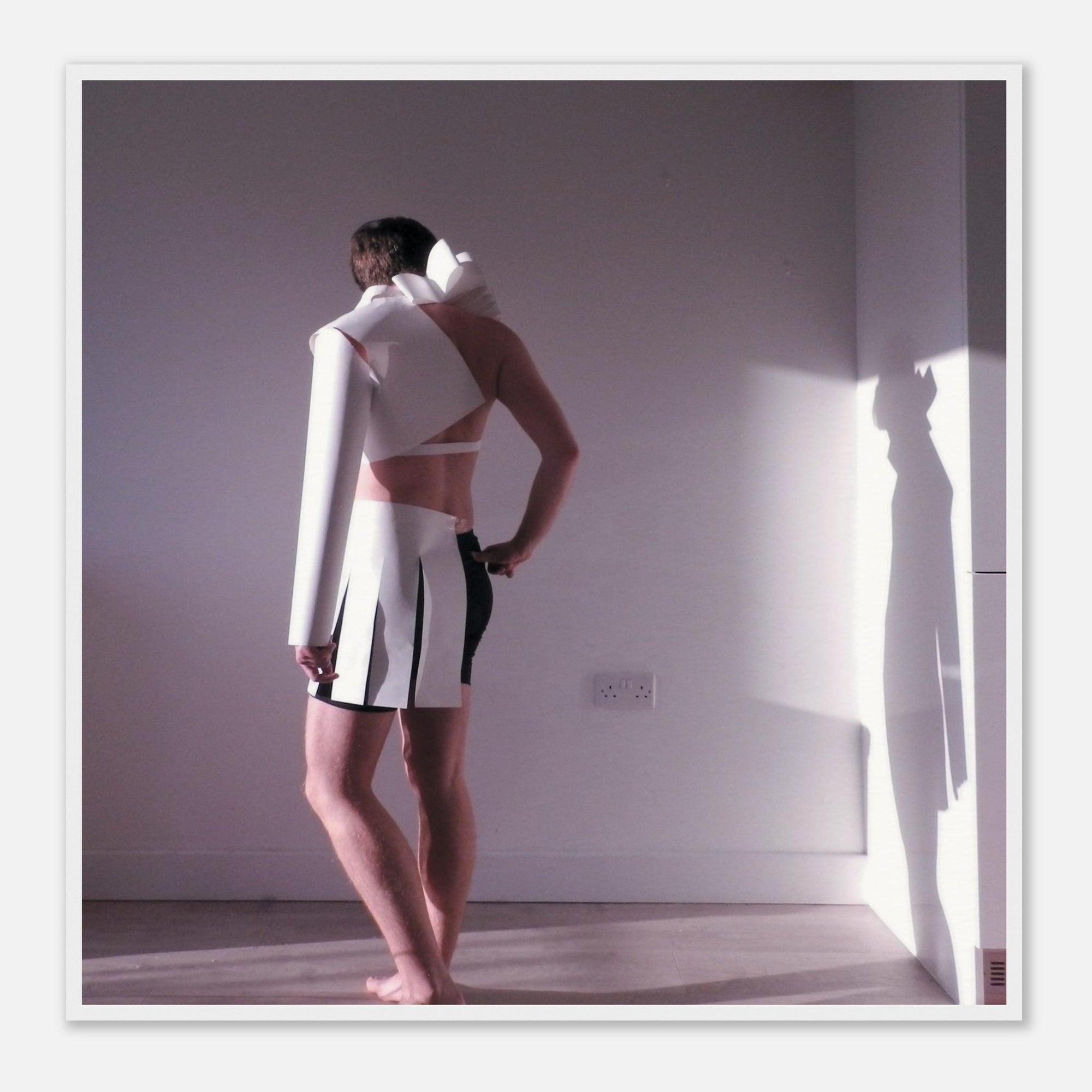 Photo art print of a person wearing a white outfit with black accents in a minimal room.