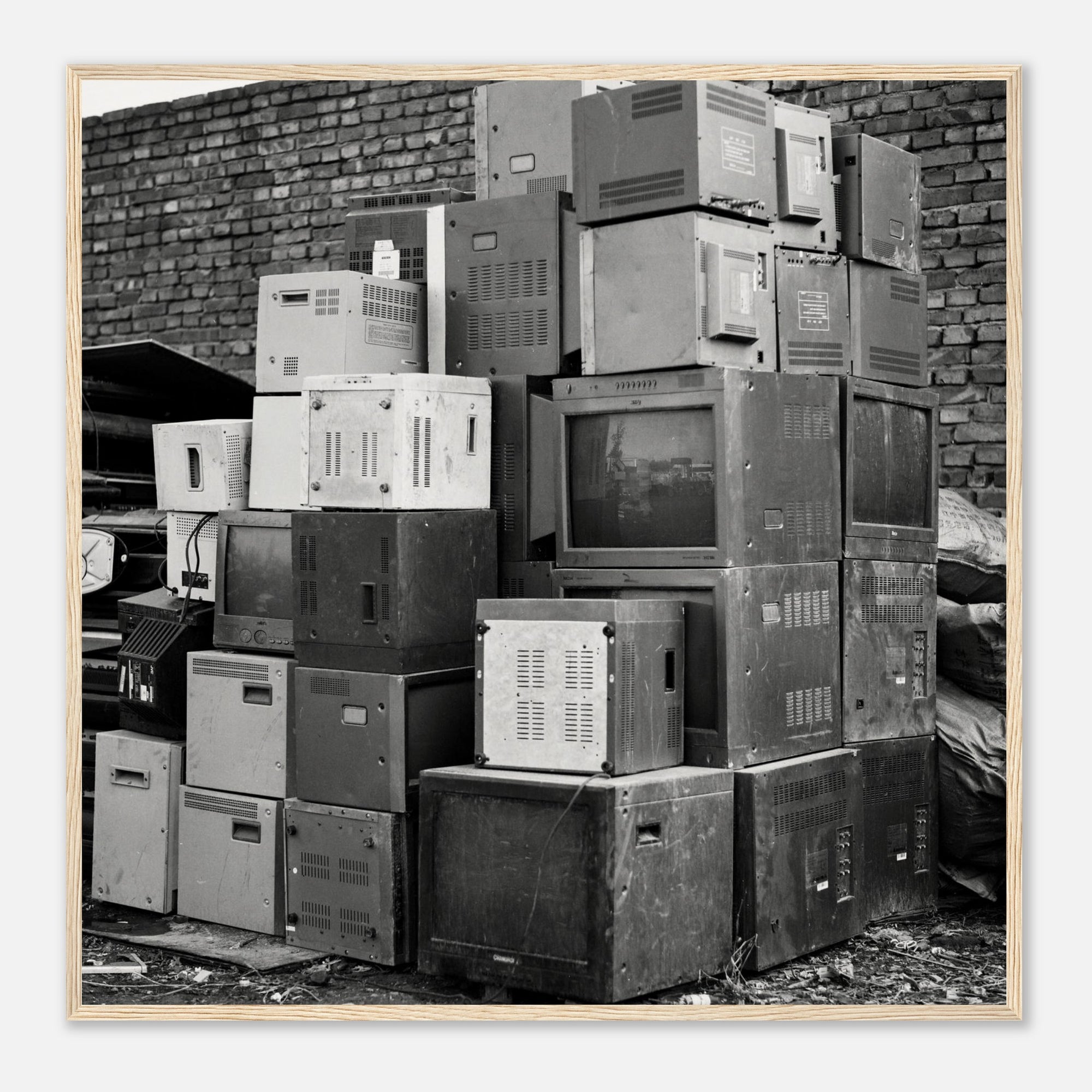 Framed black and white photo of a stack of old electronic equipment against a brick wall
