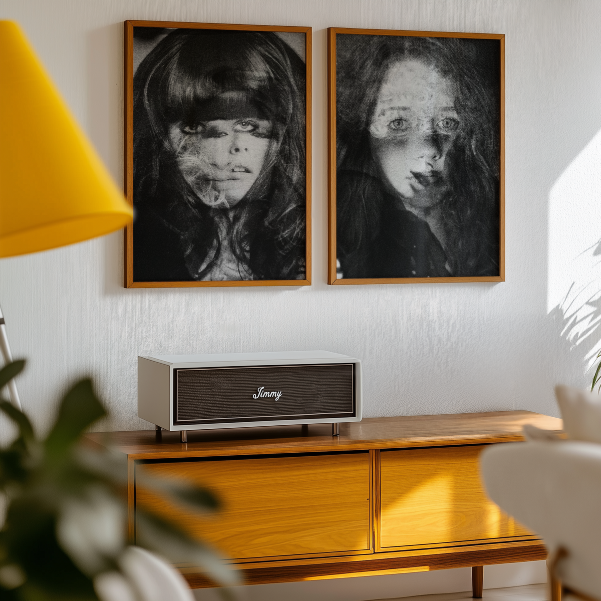 Two framed black and white portraits above a wooden cabinet with a JVC speaker.