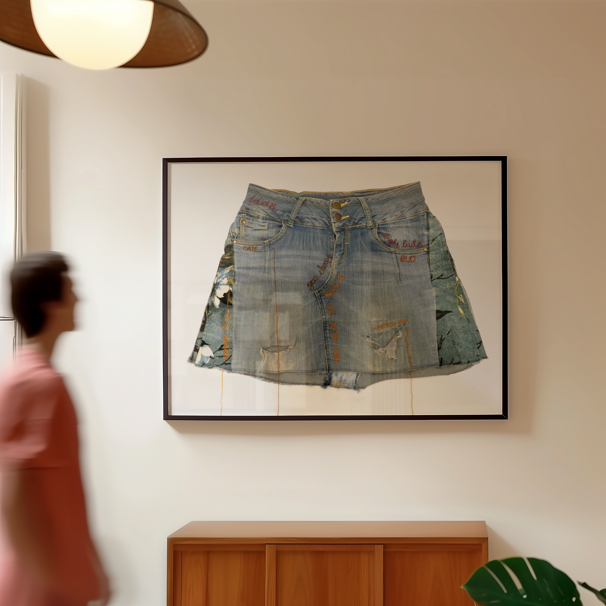 Framed denim skirt on a wall with a person walking by