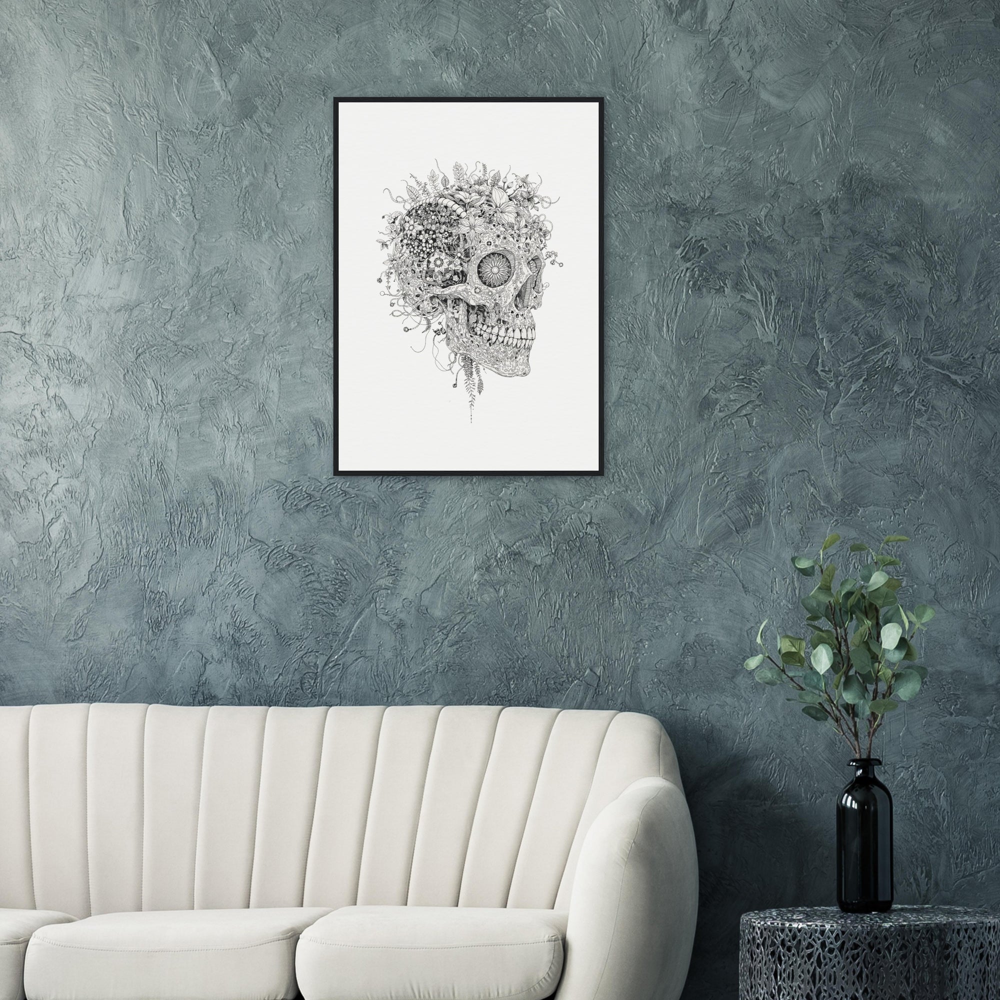 Skull art print on a gray wall above a white sofa with a vase of greenery on a side table.