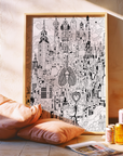 Framed black and white cityscape art on a wall with pillows and drinks below