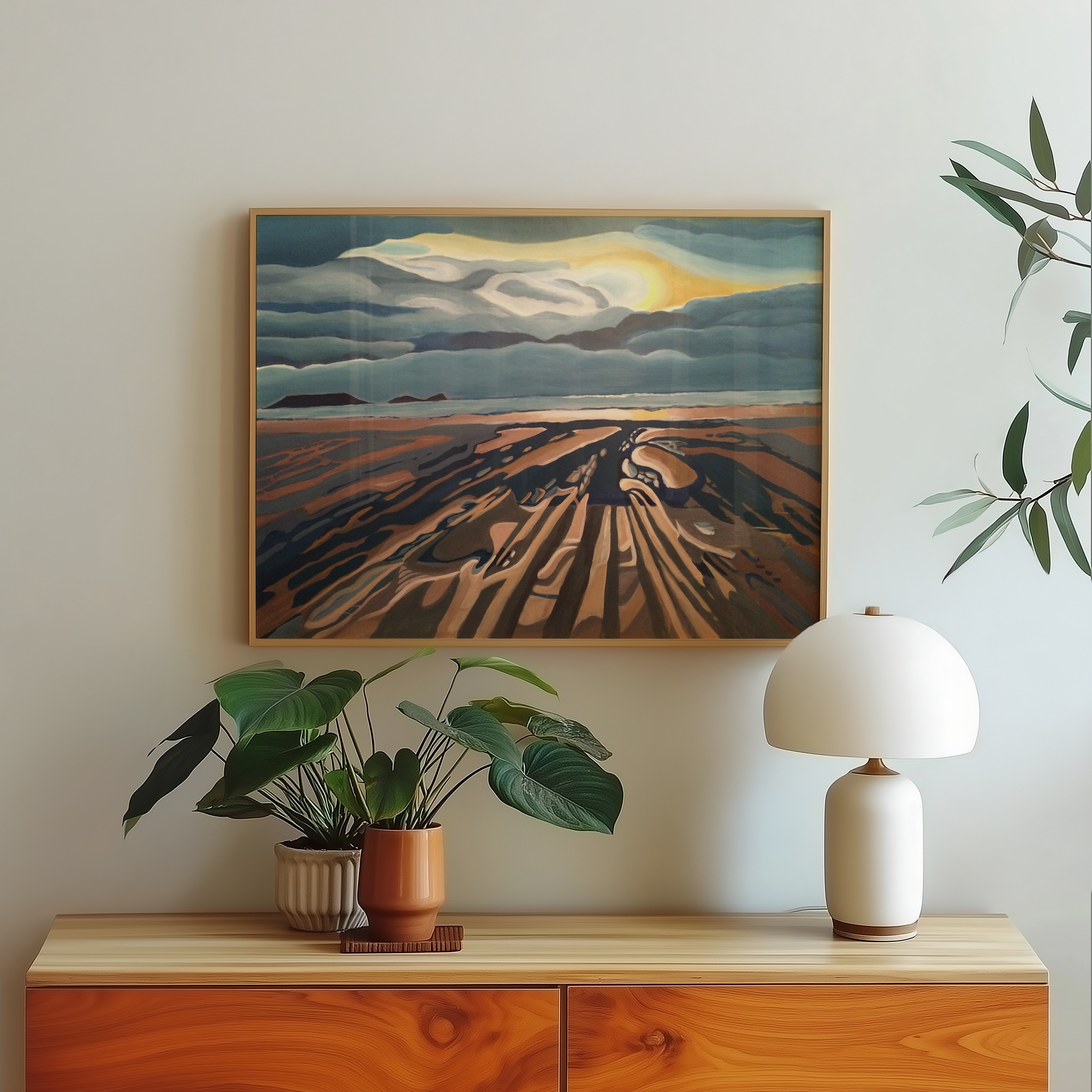 Framed art print of worms head in wales hanging on a wall above a side table with lamp and plants.